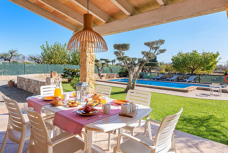 Terrasse mit Esstisch und Poolblick